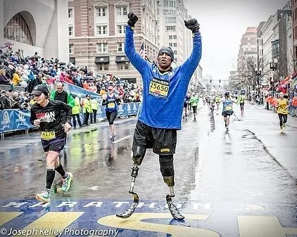 Cedric King finishing the Boston Marathon with arms raised