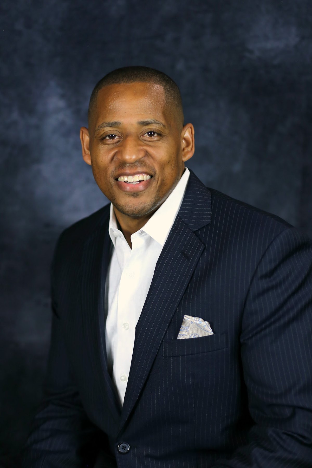 Studio headshot of motivational speaker Cedric King in a navy pinstripe suit